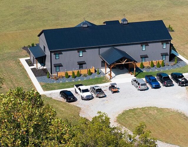 Gray metal barn-style home with parking area, modern farmhouse design, and manicured landscaping for demo showcasing.